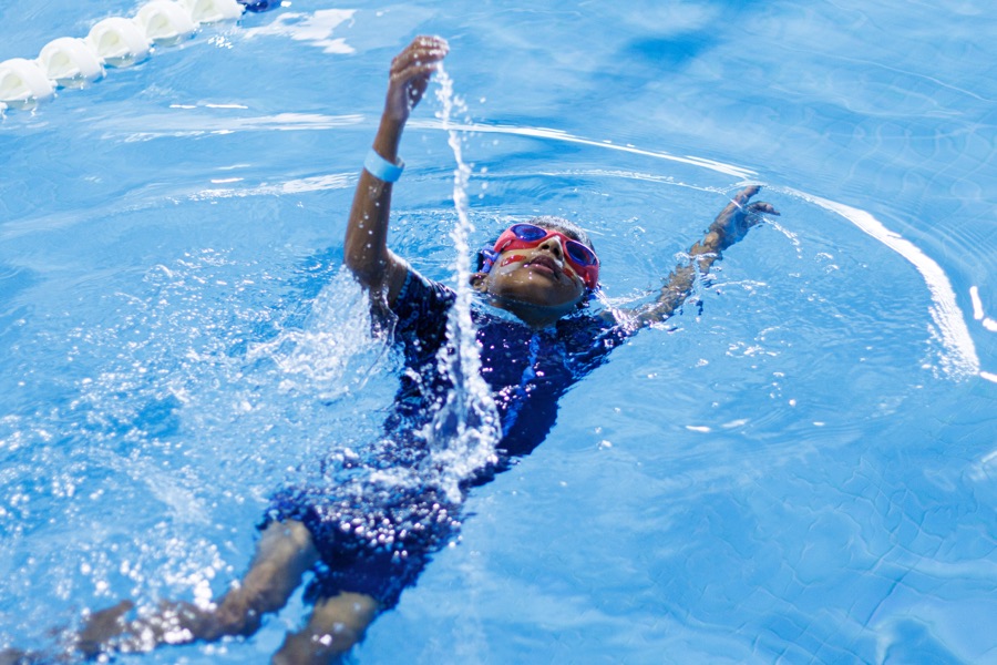 Underwater view of a child swimming backstroke, arm extended overhead