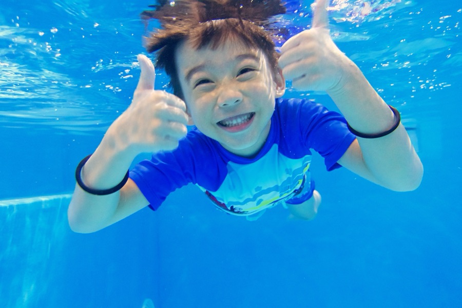 A boy underwater giving a thumbs up